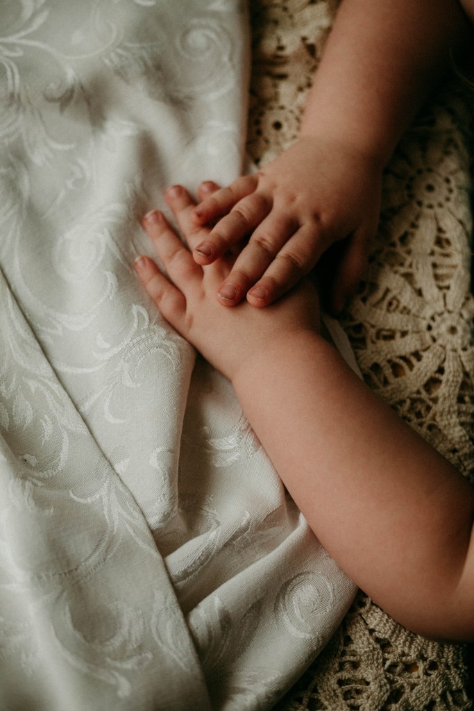 A young girl's hands resting gently on a vintage lace tablecloth, capturing a moment of connection during a family Sunday dinner.