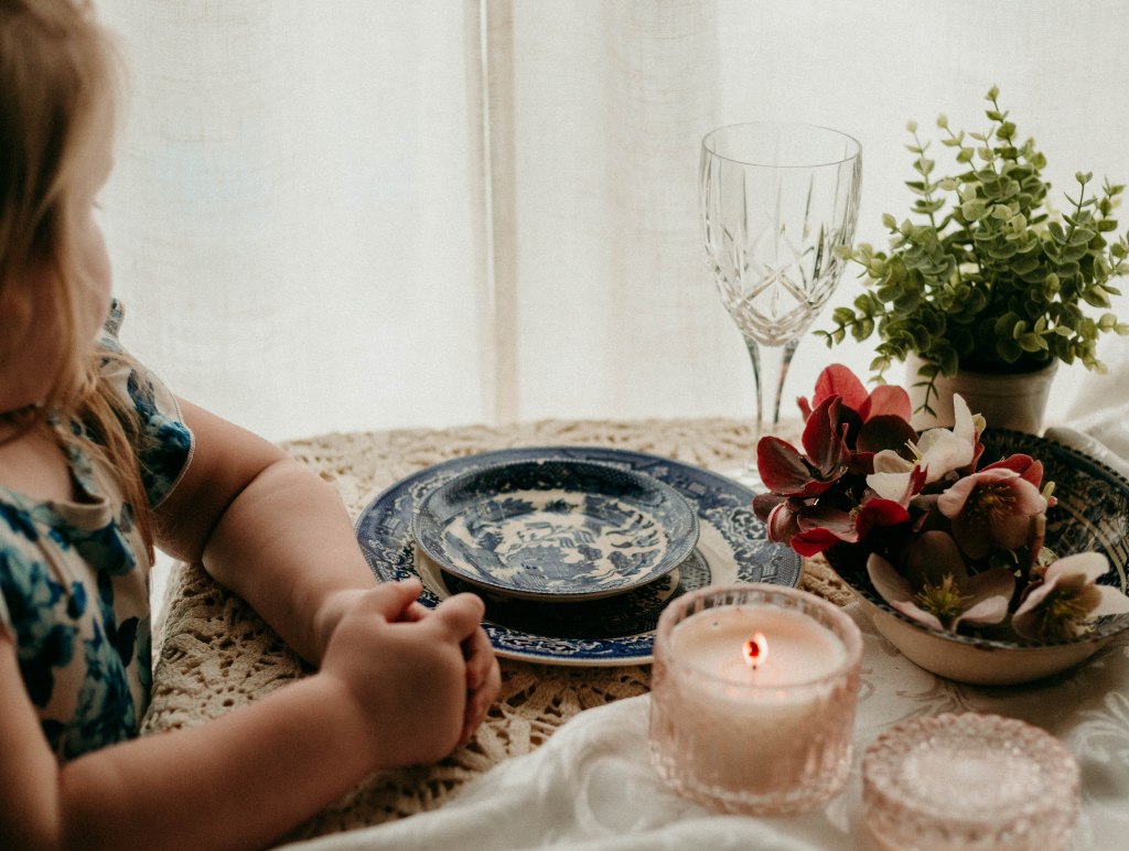 Vintage crystal water goblet and fresh greenery on a set Sunday dinner table with heirloom china.
