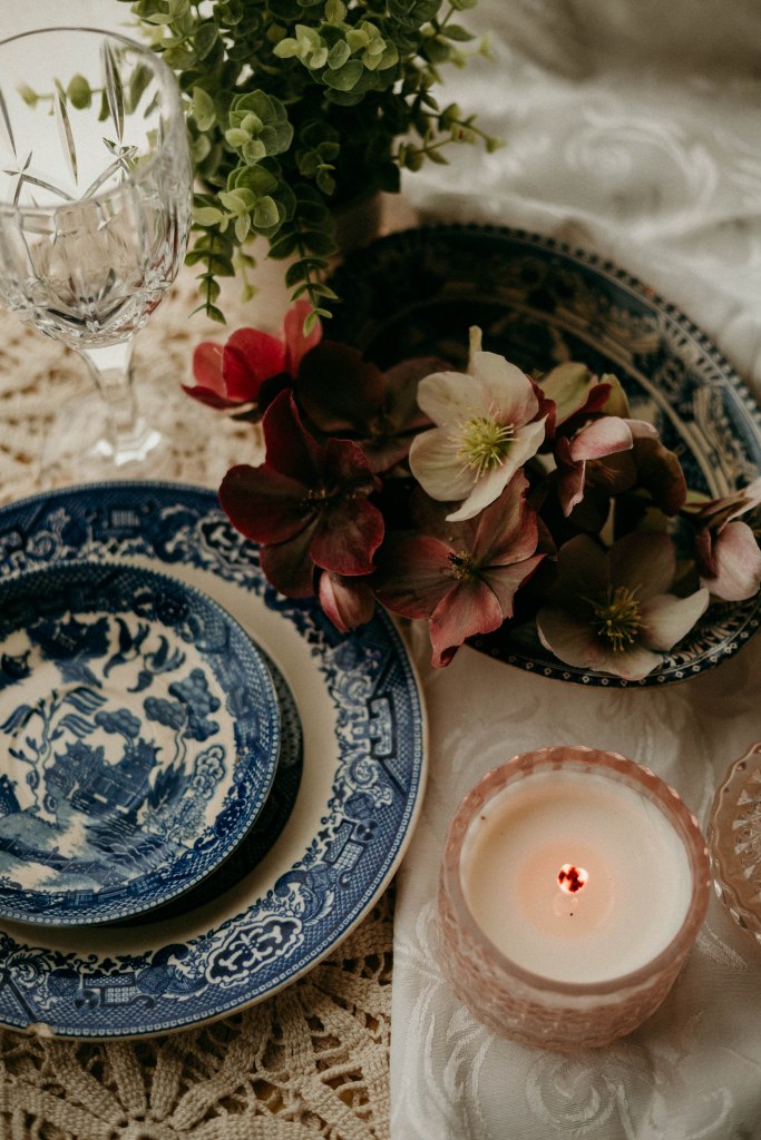 Vintage crystal water goblet and fresh greenery on a set Sunday dinner table with heirloom china.